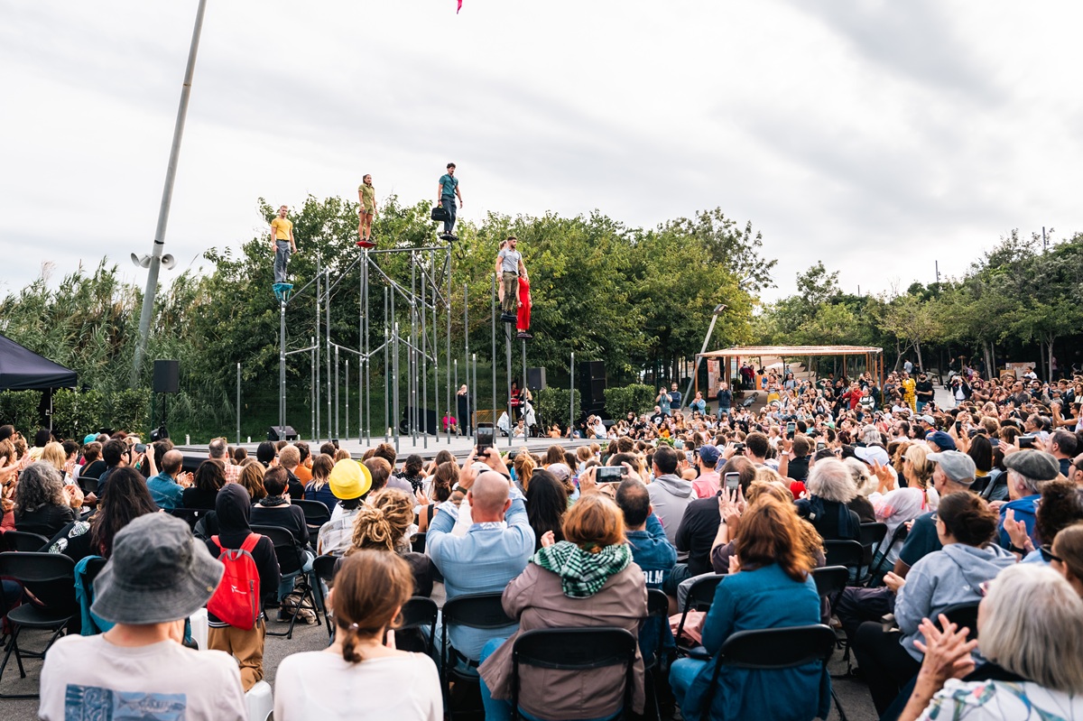 6 dancers stand on poles up to 5 meters high with large crowd watching